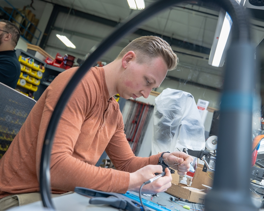 Engineer assembling a small electronic component at a workbench