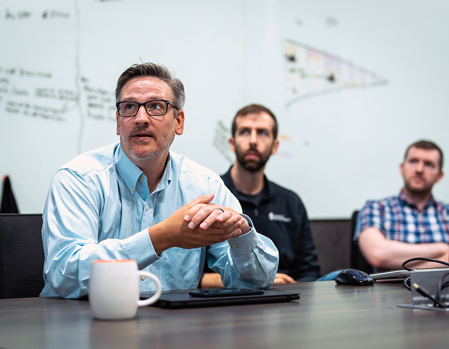 Guys looking off in the distance at a television during a conference call