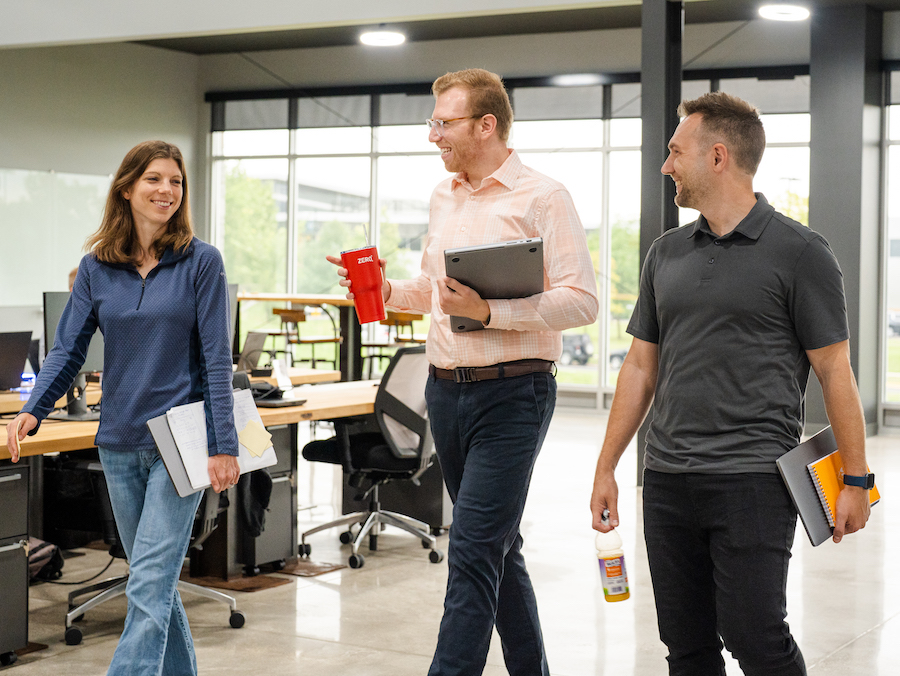 Three i3 team members walking and talking through the open office