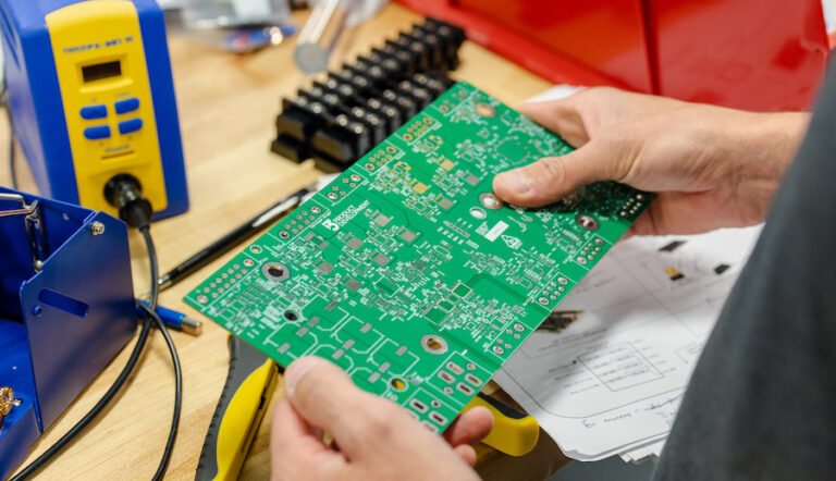Hands holding a PCB board designed by i3 Product Development