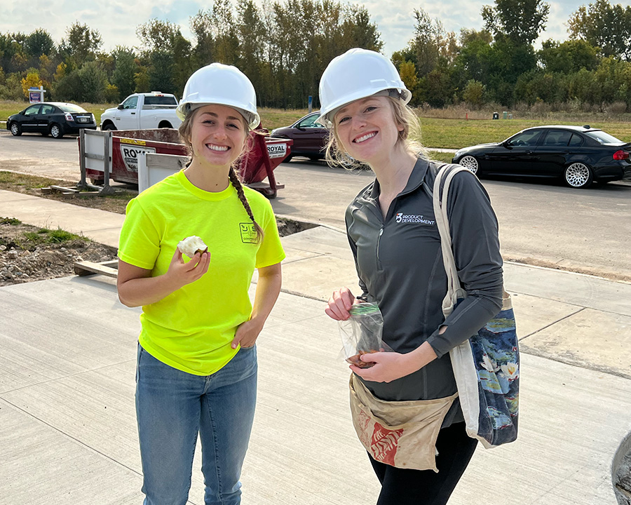Two i3 female employees smiling at the camera on site at a Habitat for Humanity job site