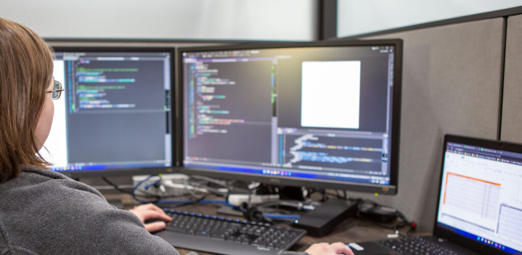 Developer at computer with multiple monitors and code on the screen