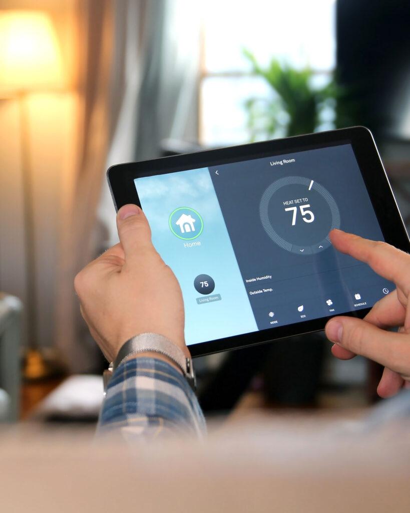 Hand holding a tablet showing a smart home app