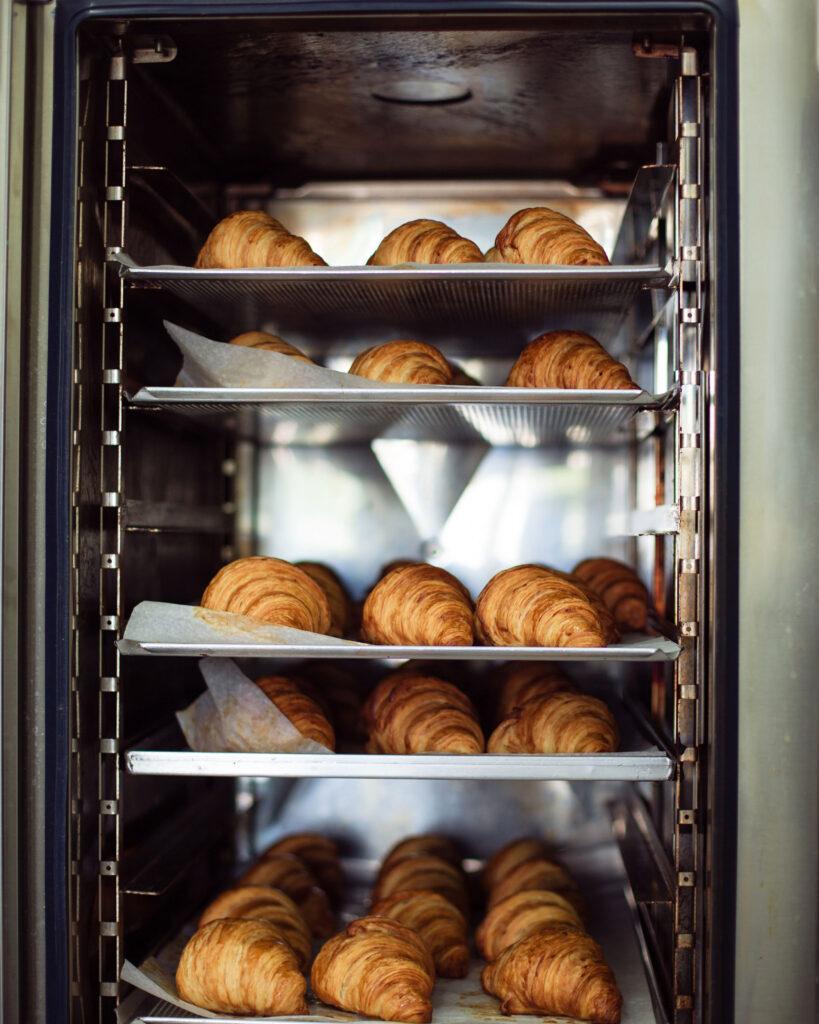 Trays of fresh croissants on a commercial kitchen rack
